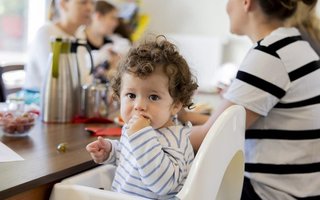 Kleines Kind im Hochstuhl beim Familienfrühstück