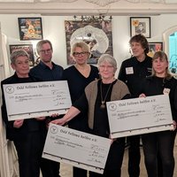 Menschen zeigen große Schecks aus Karton in der Hand und lächeln