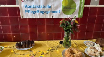 buffet mit blumenstrauß und schild kontaktstelle pflegeengagement
