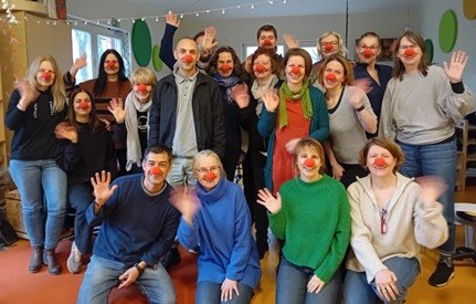 Foto vom Team der Kita unter den Kastanien mit roten Clownsmasken