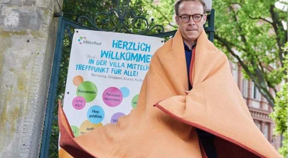 Geschäftsführer Markus in eine Wolldecke gehüllt vor Villa Mittelhof