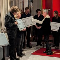 Menschen stehen zusammen und halten große Schecks aus Karton in der Hand